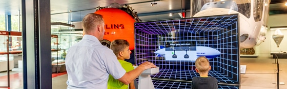 Un père et ses deux fils essaient le simulateur de vol en dirigeable. 