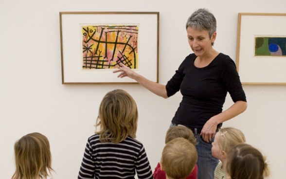 Una donna spiega un dipinto a un gruppo di bambini