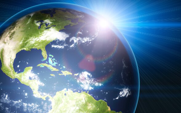 Immagine simbolica: sole dietro il pianeta terra.
