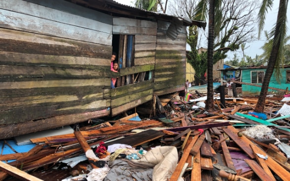 Dos niñas se asoman a la ventana de su casa tras el paso del huracán Iota mientras sus vecinos recogen los escombros de sus viviendas en el barrio El Muelle, Puerto Cabezas, costa Caribe norte de Nicaragua.