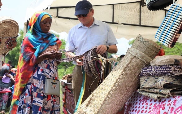 TASAF beneficiary from Ruvu Darajani in Chalinze District explains her craft to Ambassador Randin. 