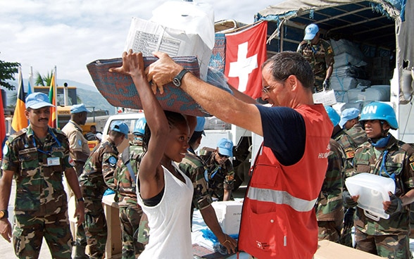 Un miembro del Cuerpo Suizo de Ayuda Humanitaria (CSA) distribuye material de socorro.