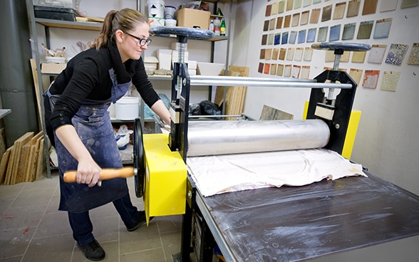 A worker winding a sheet of aluminium into a roll.