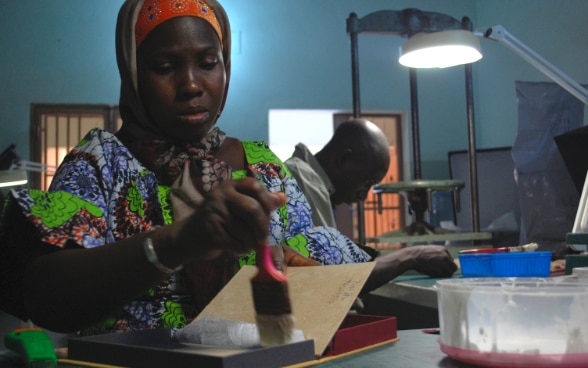 A Malian woman making a solander box.