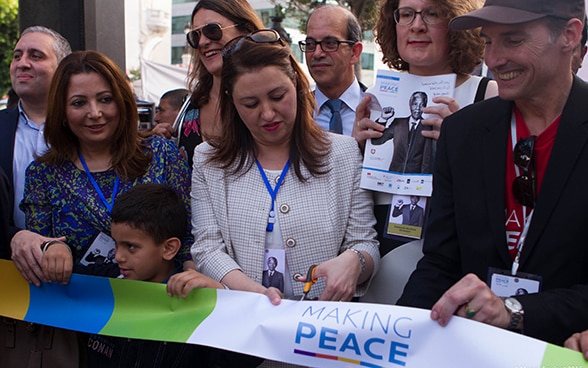 Surrounded by a group of people, the Tunisian culture minister cuts a ribbon.