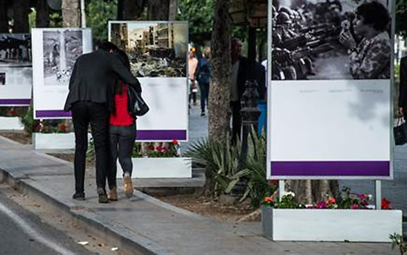 Un couple marche à côté de photos de l’exposition.
