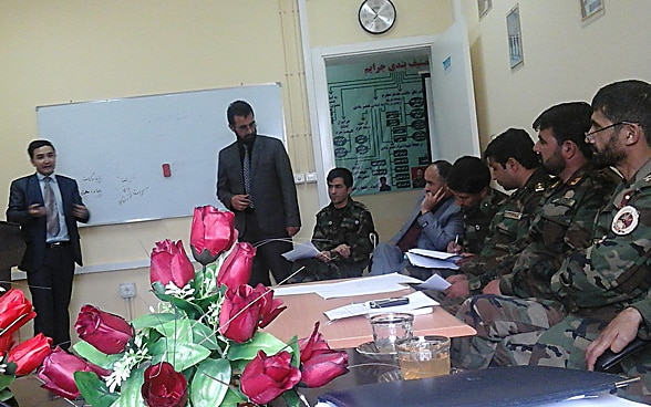 A human rights defender briefs members of the Afghan army who are dressed in military uniform.