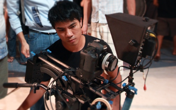 Ein junger myanmarischer Filmemacher bei Dreharbeiten hinter der Kamera.
