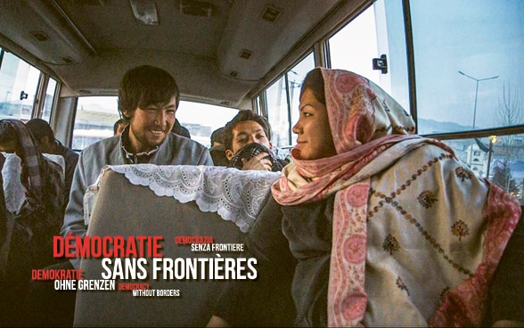Szene aus dem Film «Laila at the Bridge». Ein Mann und eine Frau sitzen in Afghanistan einem Bus. Sie lachen. Im Hintergrund sind Berge zu sehen. 