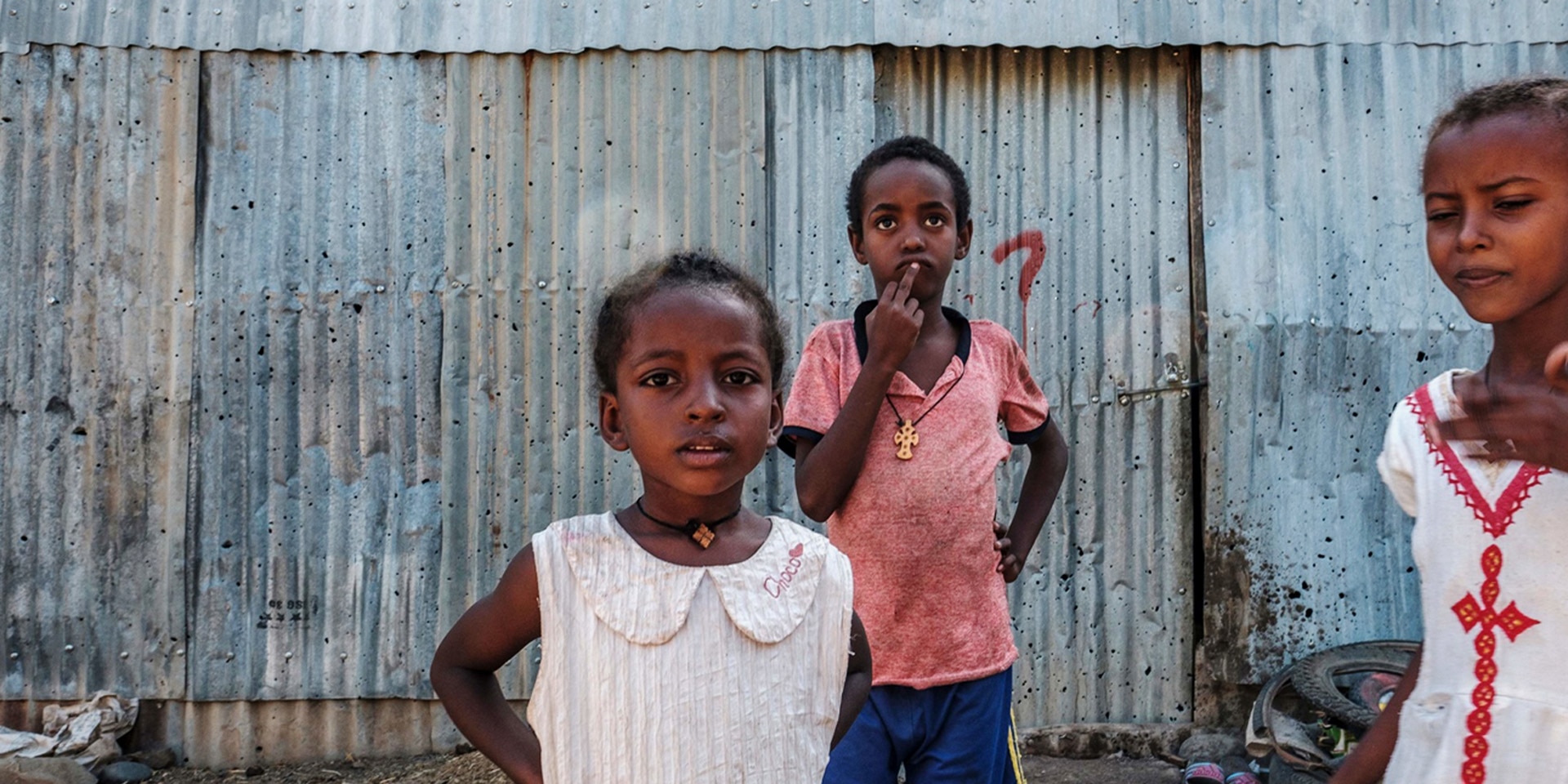 Mädchen stehen vor einer Blechhütte in Humera, Äthiopien.