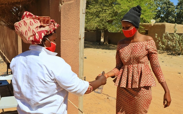 Deux femmes africaines portent des masques et se désinfectent les mains à cause du Covid-19.