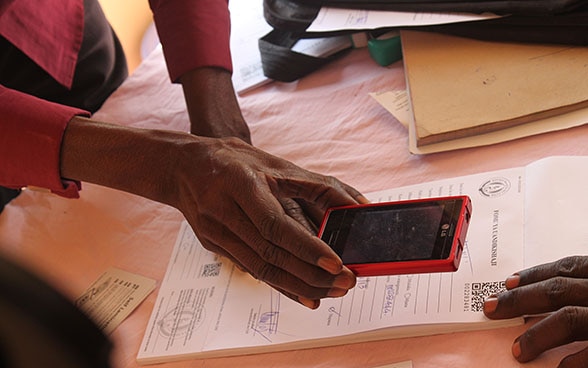  Eine Frau scannt mit ihrem Mobiltelefon einen QR-Code auf einem Blatt Papier. 
