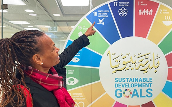 Patricia Danzi zeigt auf eines der 17 Ziele für nachhaltige Entwicklung der UNO, die auf einer kreisförmigen Tafel angeordnet sind.