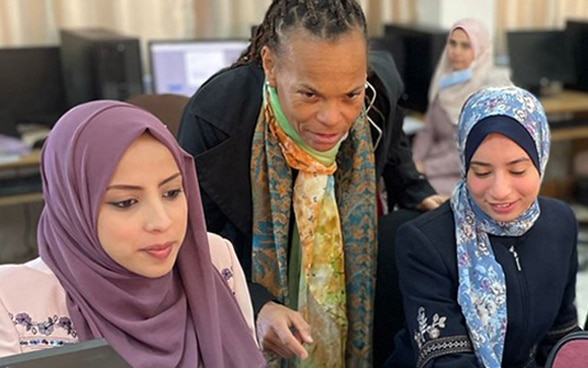 Patricia Danzi gives some advice to two young women working on a computer.