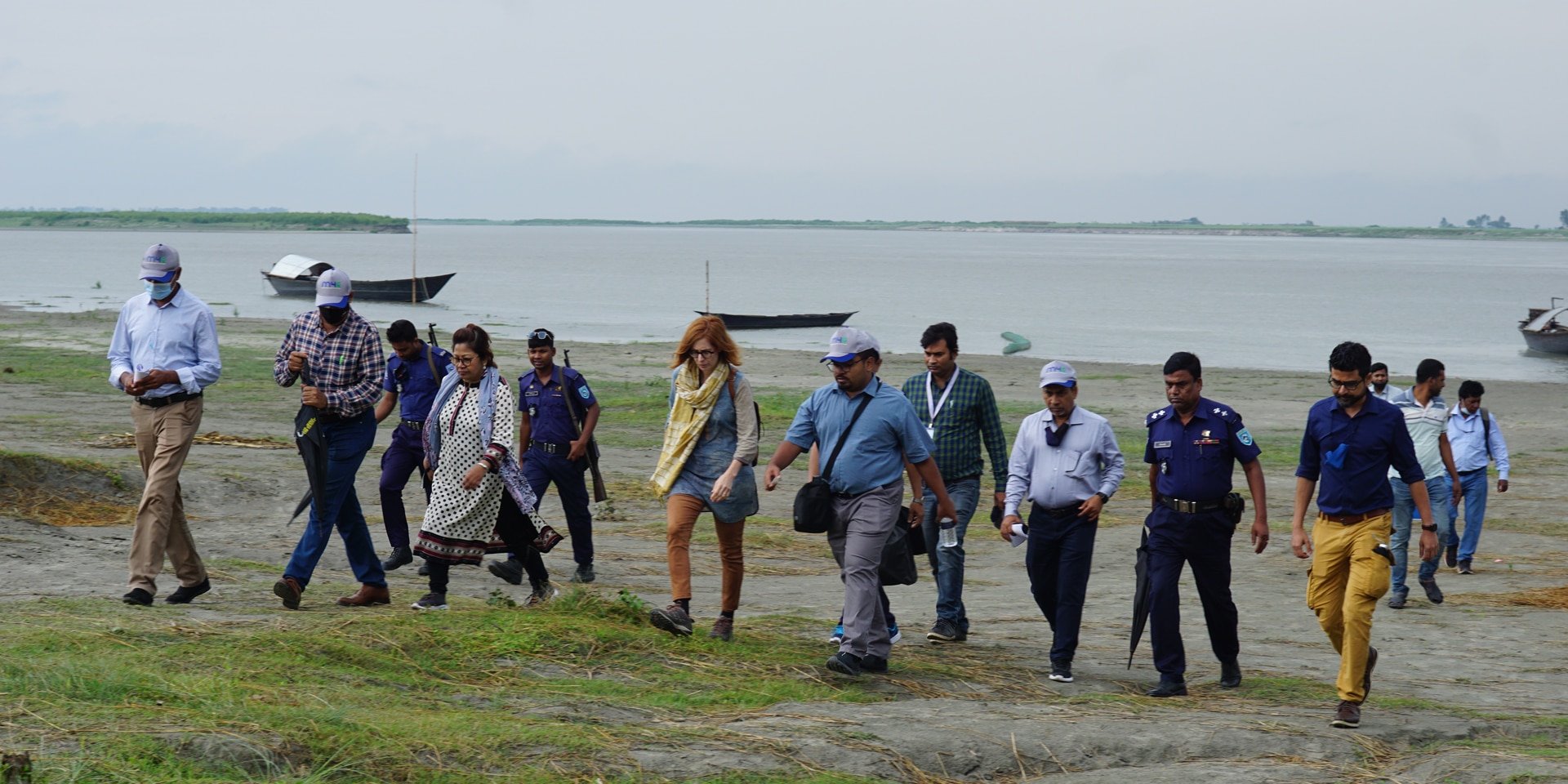 Men and women walking on a river island.