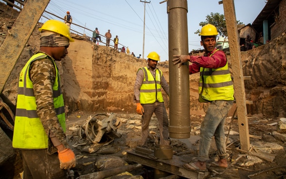 En una obra de construcción de un puente, tres obreros son fotografiados trabajando.