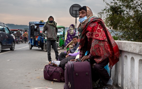 En el arcén de una carretera, nepalíes con sus maletas se preparan para emigrar a la India.
