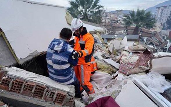 Un miembro de la Cadena de Salvamento Suiza consuela a una persona sobre los escombros de un edificio derrumbado.