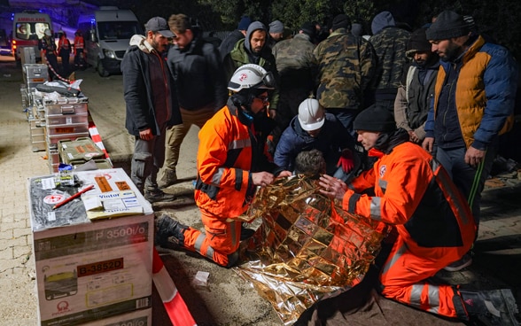 Members of the rescue chain kneel next to a girl who has just been rescued.