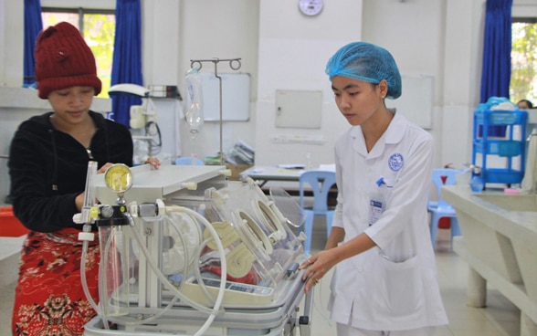 Siem Reap maternity clinic: a mother in front of her newborn with a carer. 