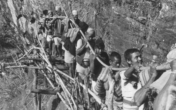 Nepalese men carry steel cables for the suspension bridge to the construction site.