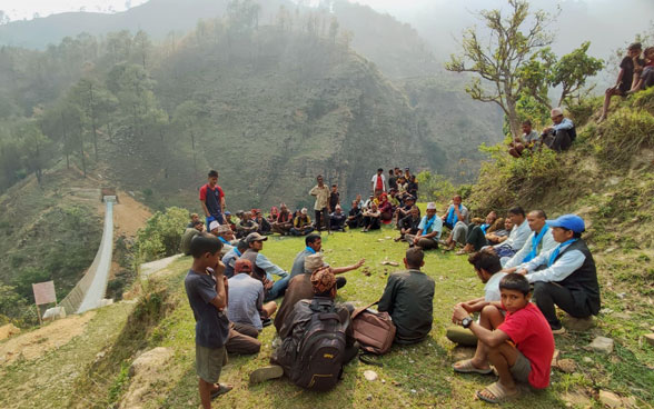 Gente sentada en círculo en una colina.