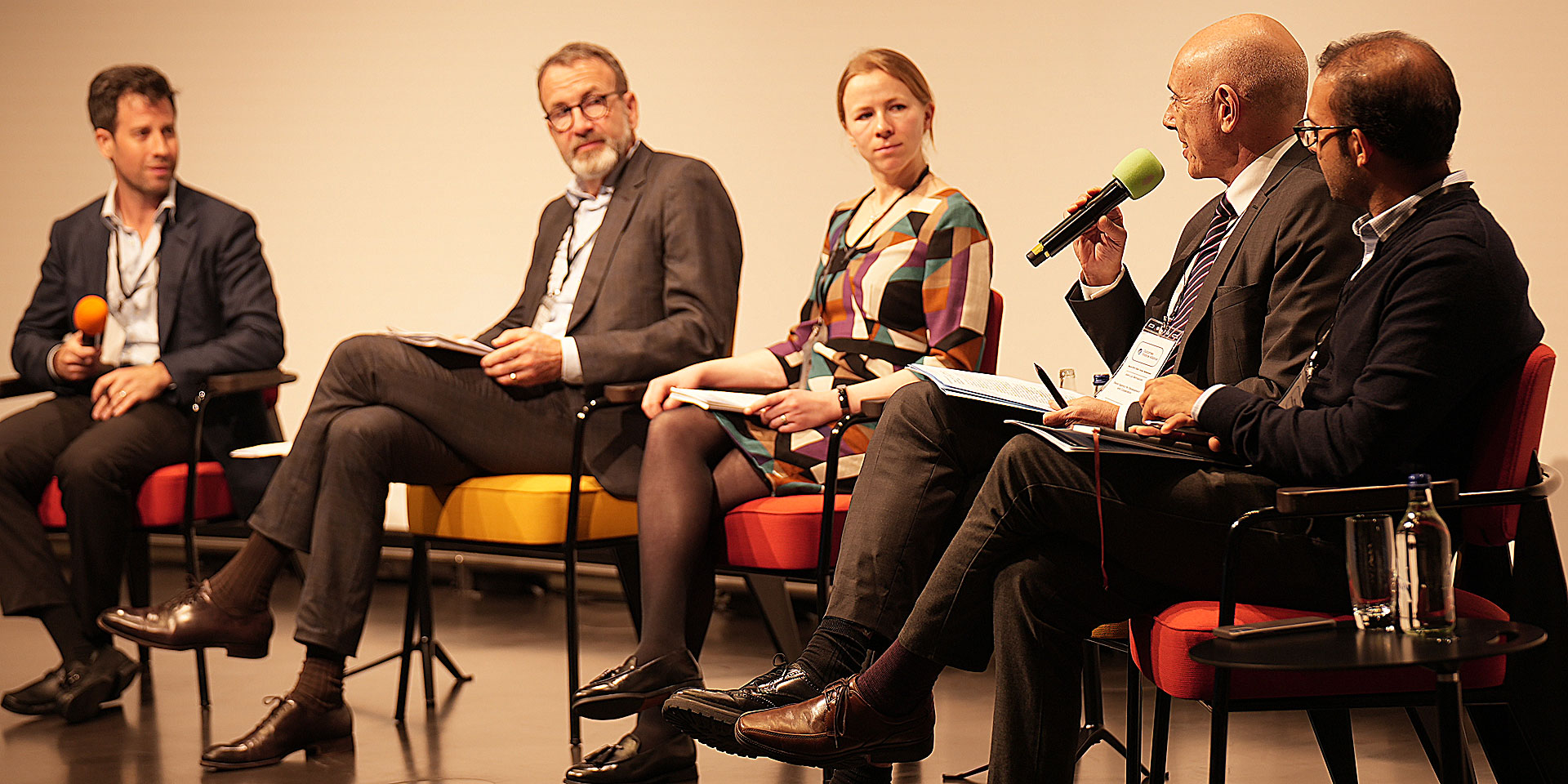   Vier Männer und eine Frau nehmen an einer Podiumsdiskussion teil.