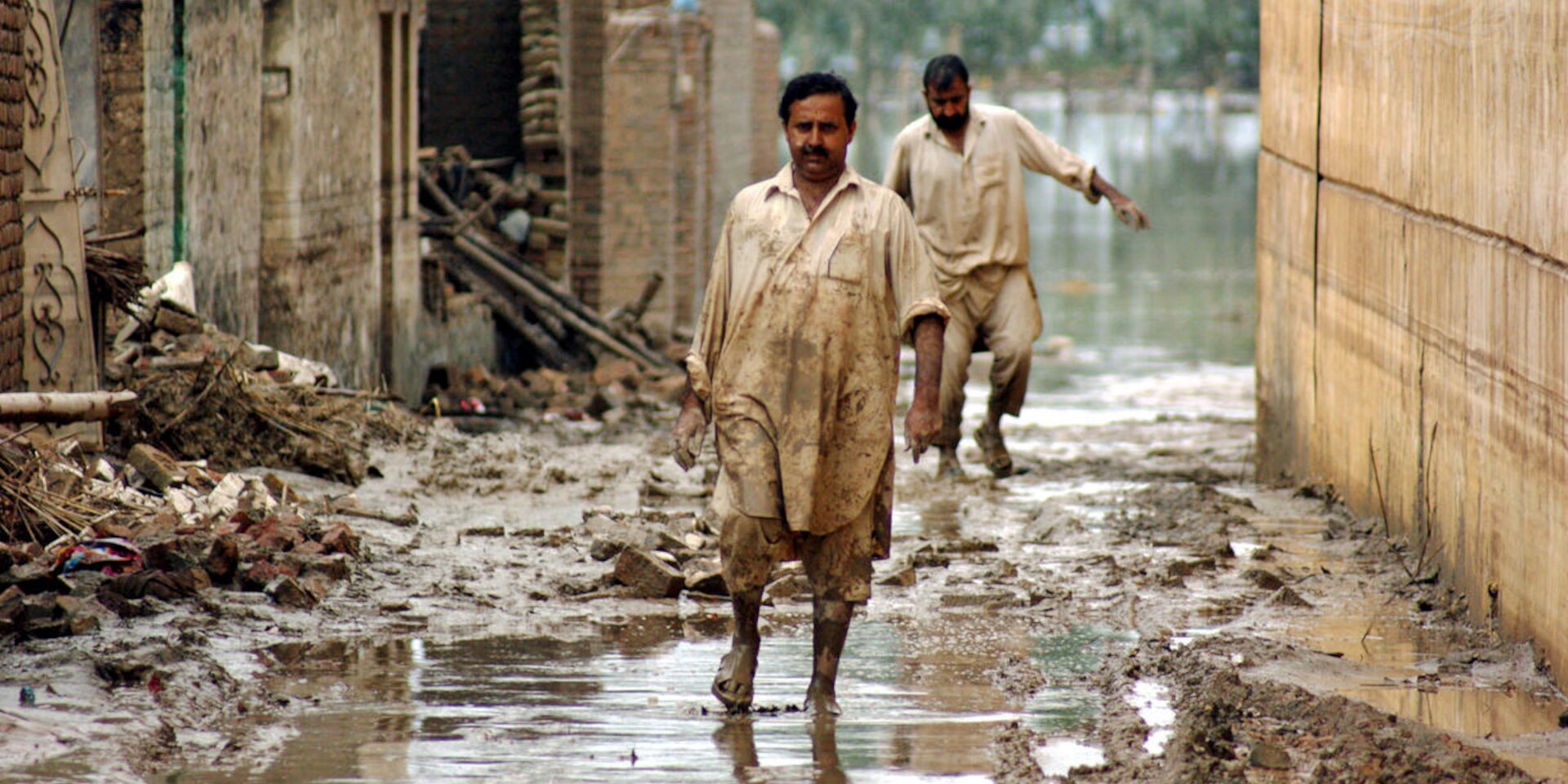Des victimes des inondations de 2010 au Pakistan marchent dans les rues inondées de la ville de Nowshera, dans le nord-ouest du pays.