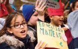 Titelseite des Weltbildungsberichts. Kinder mit Plakaten, die auf die Bedeutung von Bildung hinweisen.