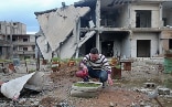 A man is watering a little garden in the midst of war in Syria.