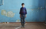 Boy smiling in a room with dilapidated walls.