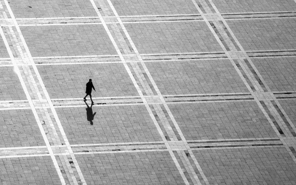 Silhouette d’une personne traversant une place. 