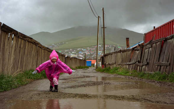 Enfant marchant sous la pluie dans une rue boueuse du quartier des yourtes à Oulan-Bator.