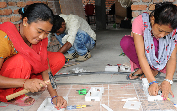 Two Nepalese women working on an electrical model.