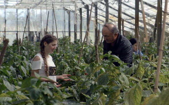 La imagen muestra a Medea y a su profesor examinando las verduras en el invernadero de la escuela de Senaki.