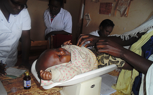 A baby being weighed in a consultation room.