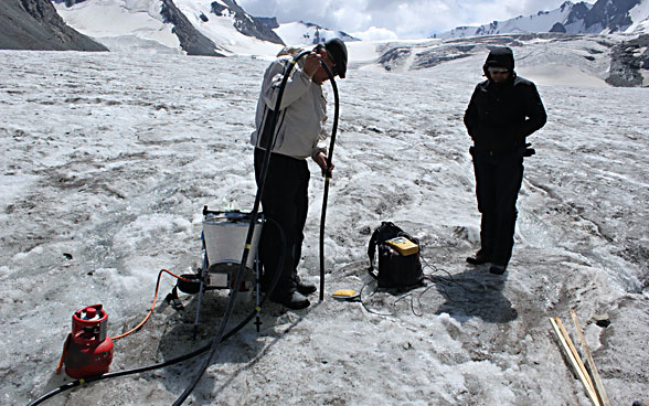 Deux hommes s’activent avec leur matériel sur un glacier.