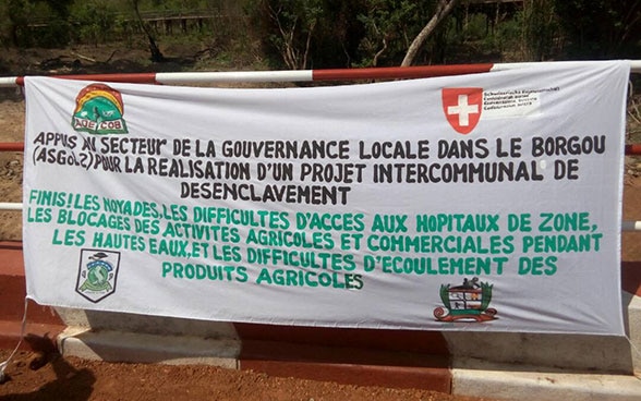 A banner with the words “Enough! No more people drowning in floods, or obstacles to hospital care, farming and trade during flooding.”