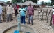 A villager in Niassa Province in northern Mozambique works a new handpump. She is surrounded by a group of people.