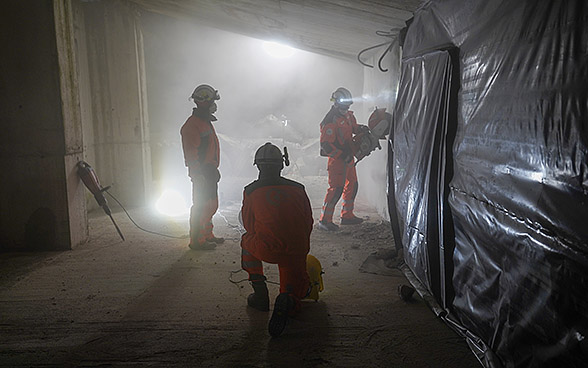 Tre soccorritori svizzeri appostati in un edificio in rovina durante un’esercitazione notturna.