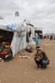 Une enfant et son père près d'une tente du HCR contenant des fruits et des légumes.