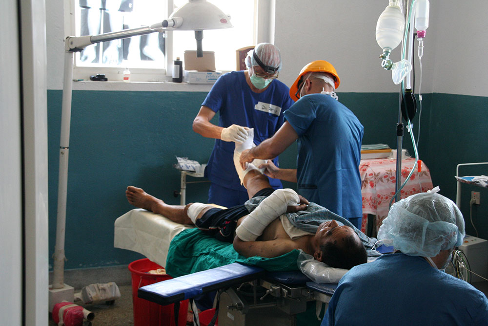 Drei Ärzte operieren ein Bein eines Verletzten in Nepal.