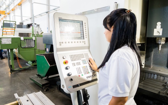 une jeune fille devant un ordinateur règle des machines.