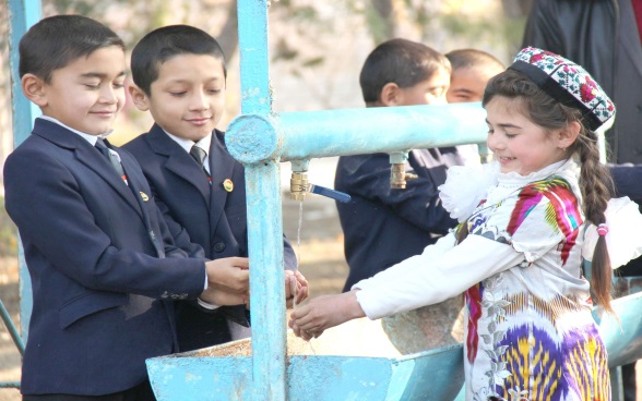 Trois enfants autour d'une fontaine.