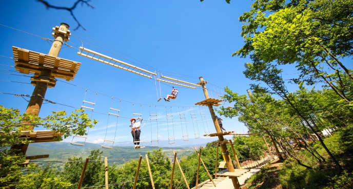 Deux personnes marchent sur des cordes à travers un parc d’escalade.