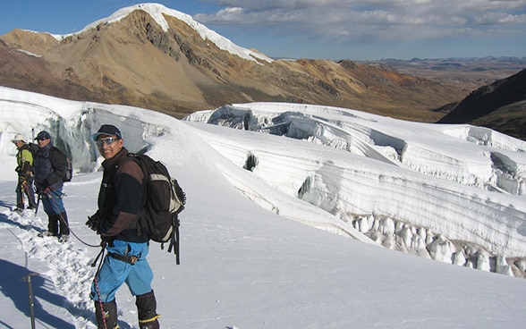 Personas caminando por una montaña de la cadena de Vilcanota en Perú.