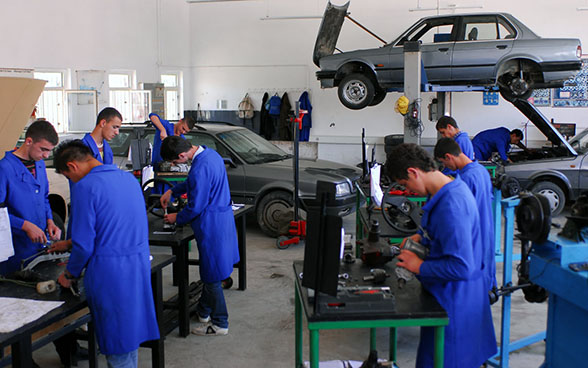 Angehende Mechaniker reparieren Autos in einer Ausbildungswerkstatt