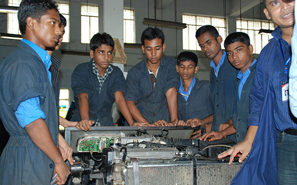 Des apprentis en mécanique écoutent un formateur dans un atelier 