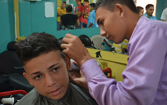 A trainee hairdresser cutting a young boy's hair