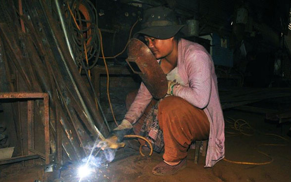 Eine Lernende beim Schweissen eines Metallteils. Sie schützt sich mit einer Maske.